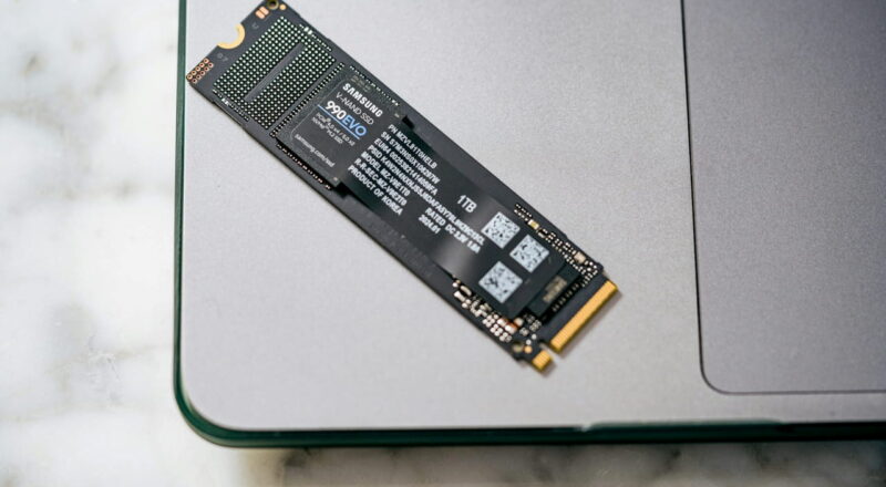 Nahaufnahme einer Samsung SSD (Solid State Drive) 990 EVO mit 1 TB Speicher, die auf einem Laptop liegt.